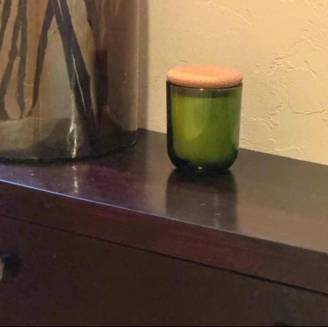 Green glass Fogborn candle with cork lid on styled wooden table