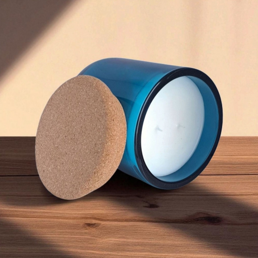 Saltmere candle in blue glass tilted to show smooth wax surface and double wicks with natural cork lid on wooden surface