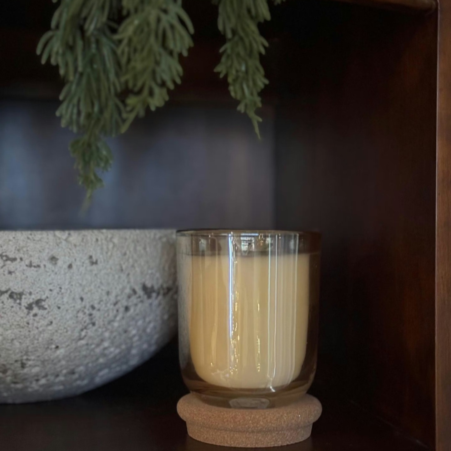 Embervine champagne colored glass candle with cork lid on styled wooden shelf with greenery