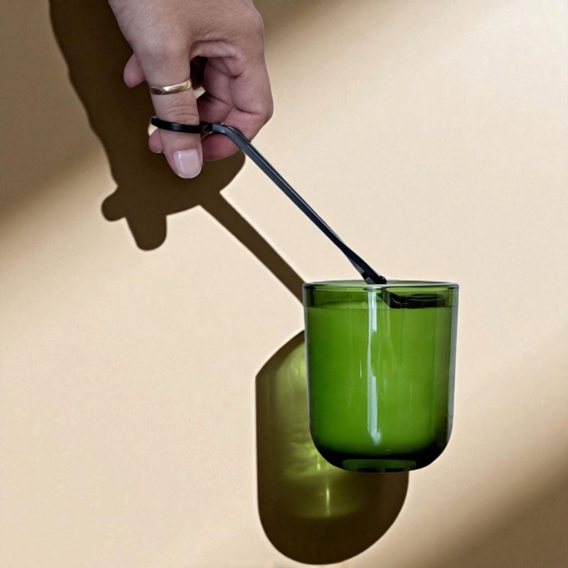 Hand trimming Fogborn candle wick with trimmers and beige background