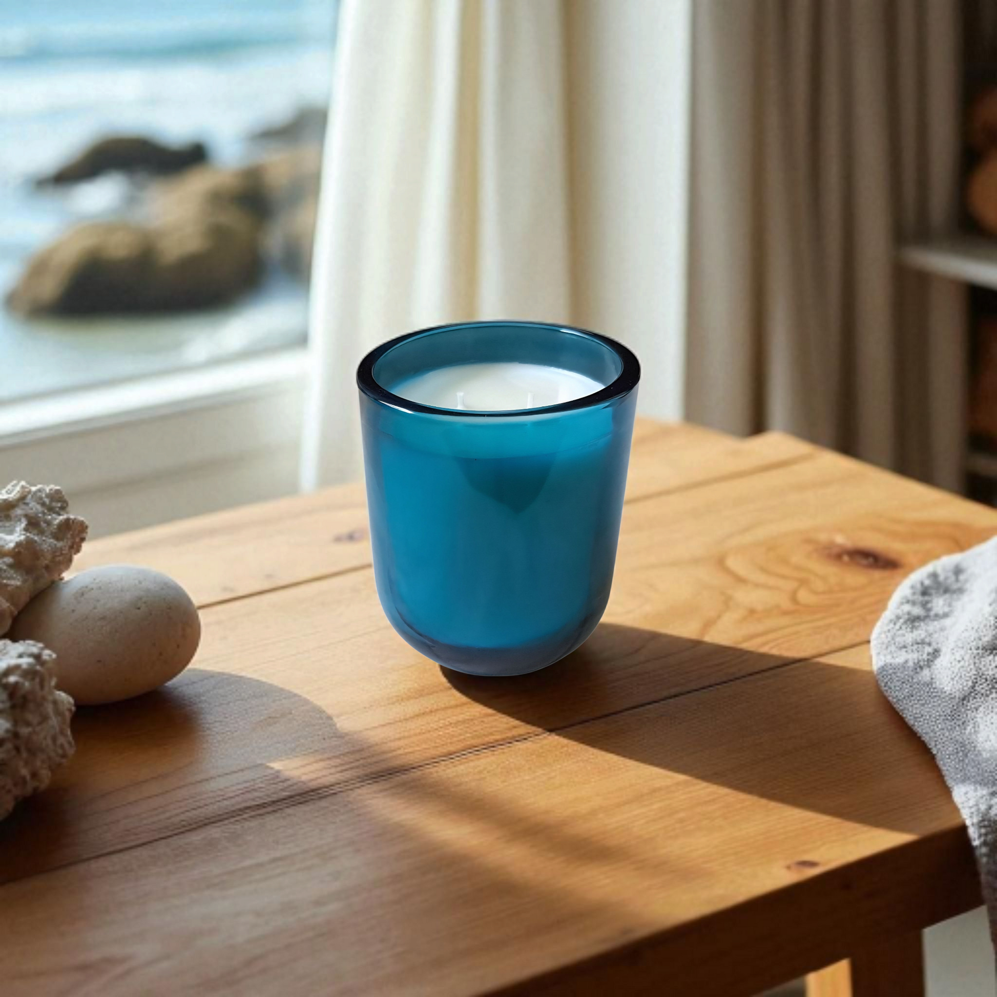 Blue glass Saltmere candle on wood surface and scenic background
