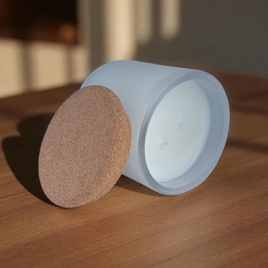 Orriswood candle in frosted white glass tilted to show natural cork lid and smooth wax surface with double wicks