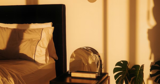 Minimalistic bedroom at golden hour with mirror and plant.