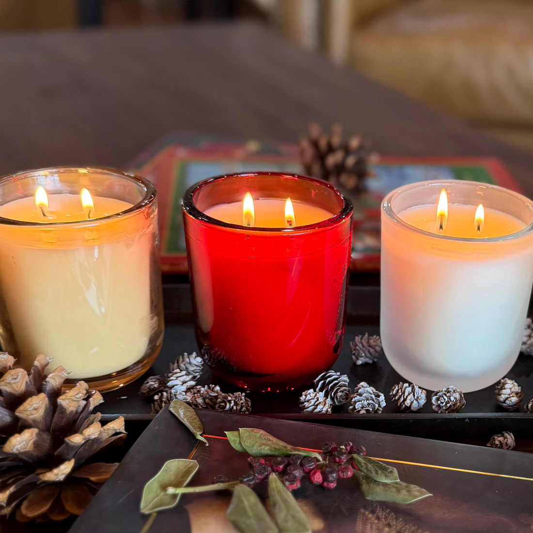 Three candles in colored and frosted glass vessels with warm candlelight, demonstrating scentscaping and candle layering