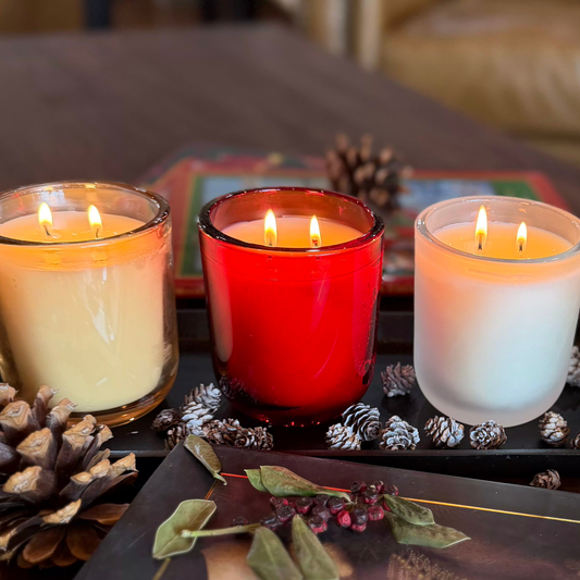 Three candles in colored and frosted glass vessels with warm candlelight, demonstrating scentscaping and candle layering