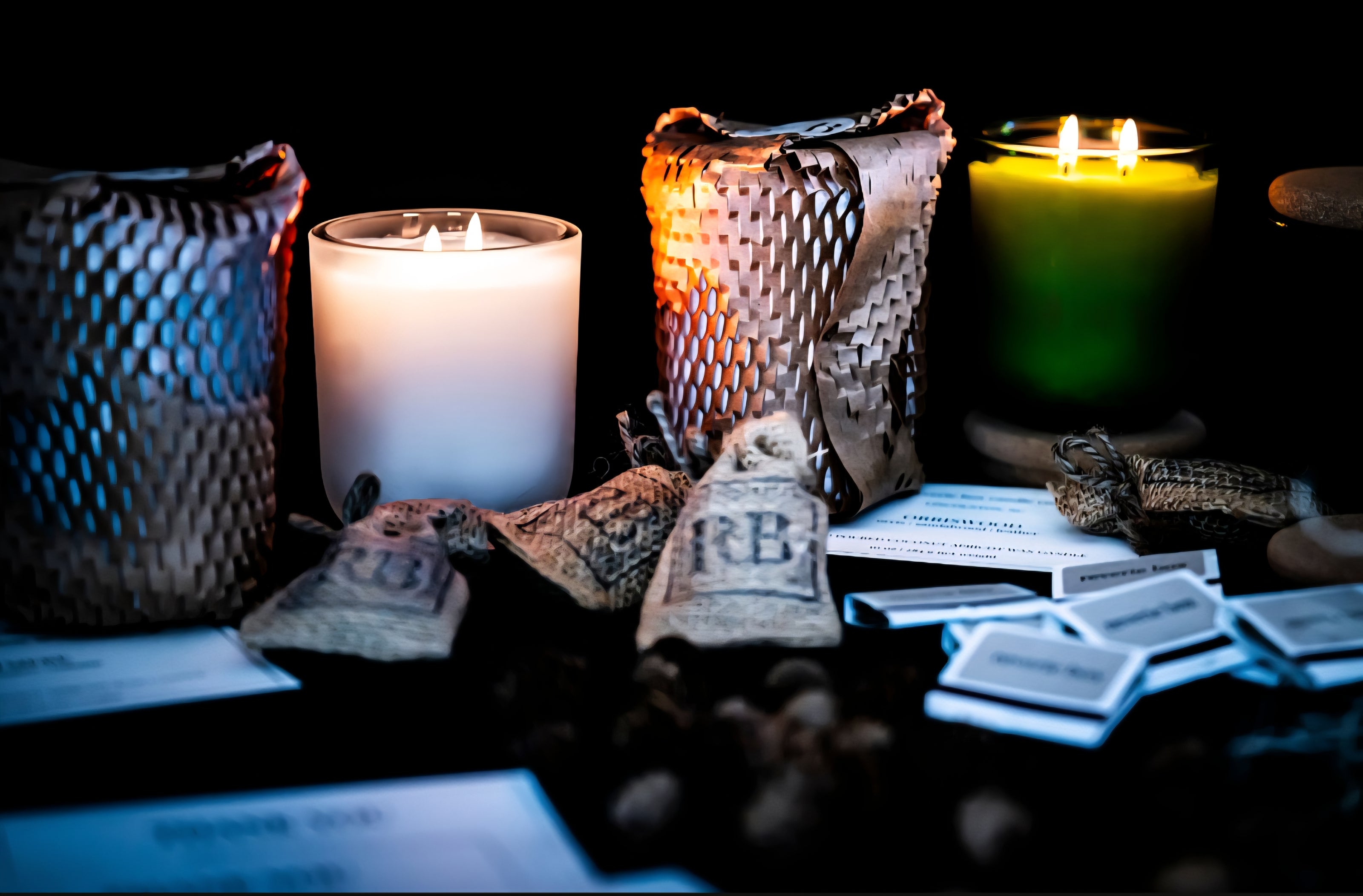candle lit scene with match books and scent sachets against dark scene