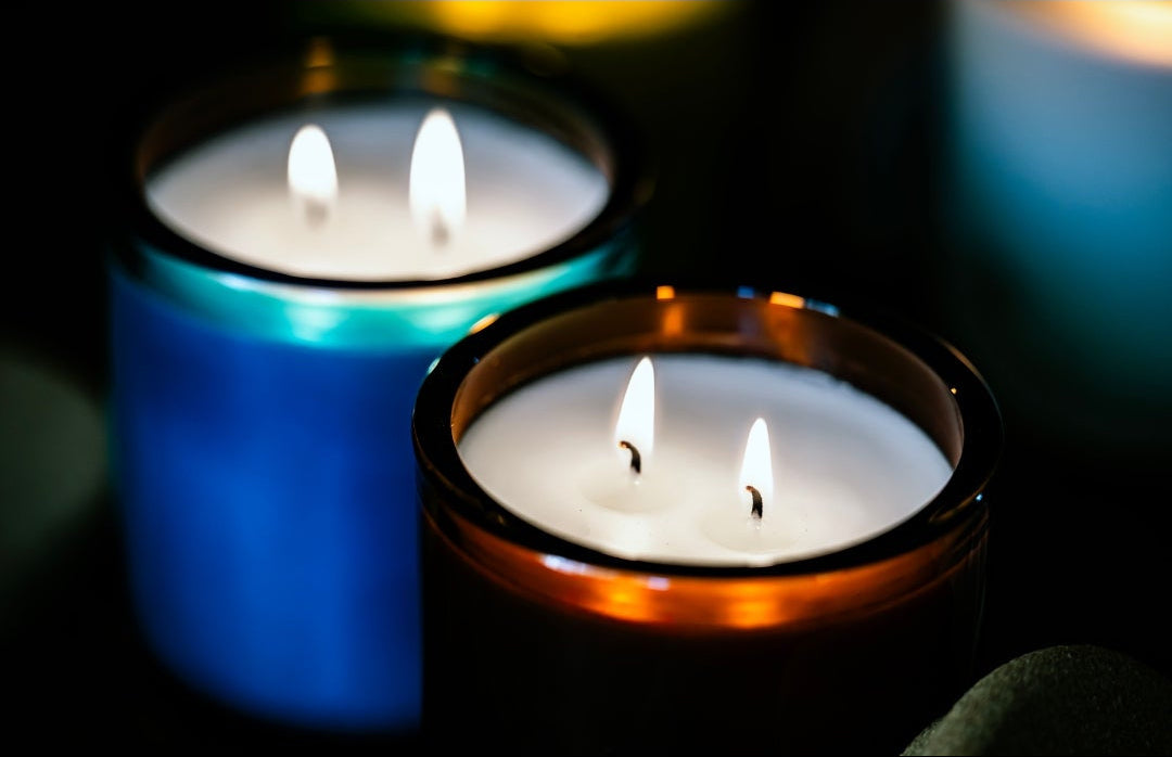 two lit candles in blue and brown with a dark background