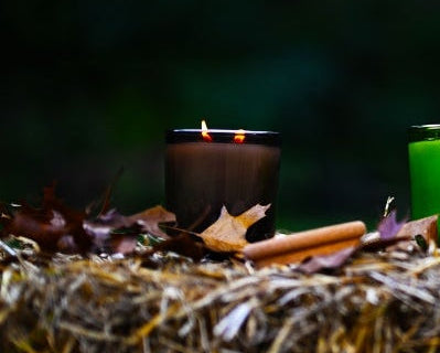 brown lit candle on hay bale with dark outside background