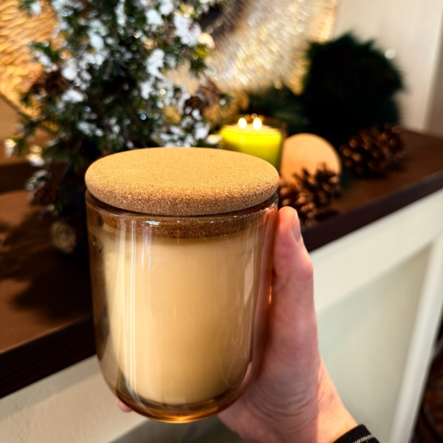 Hand holding Embervine candle product detail shot amber glass tumbler and cork lid