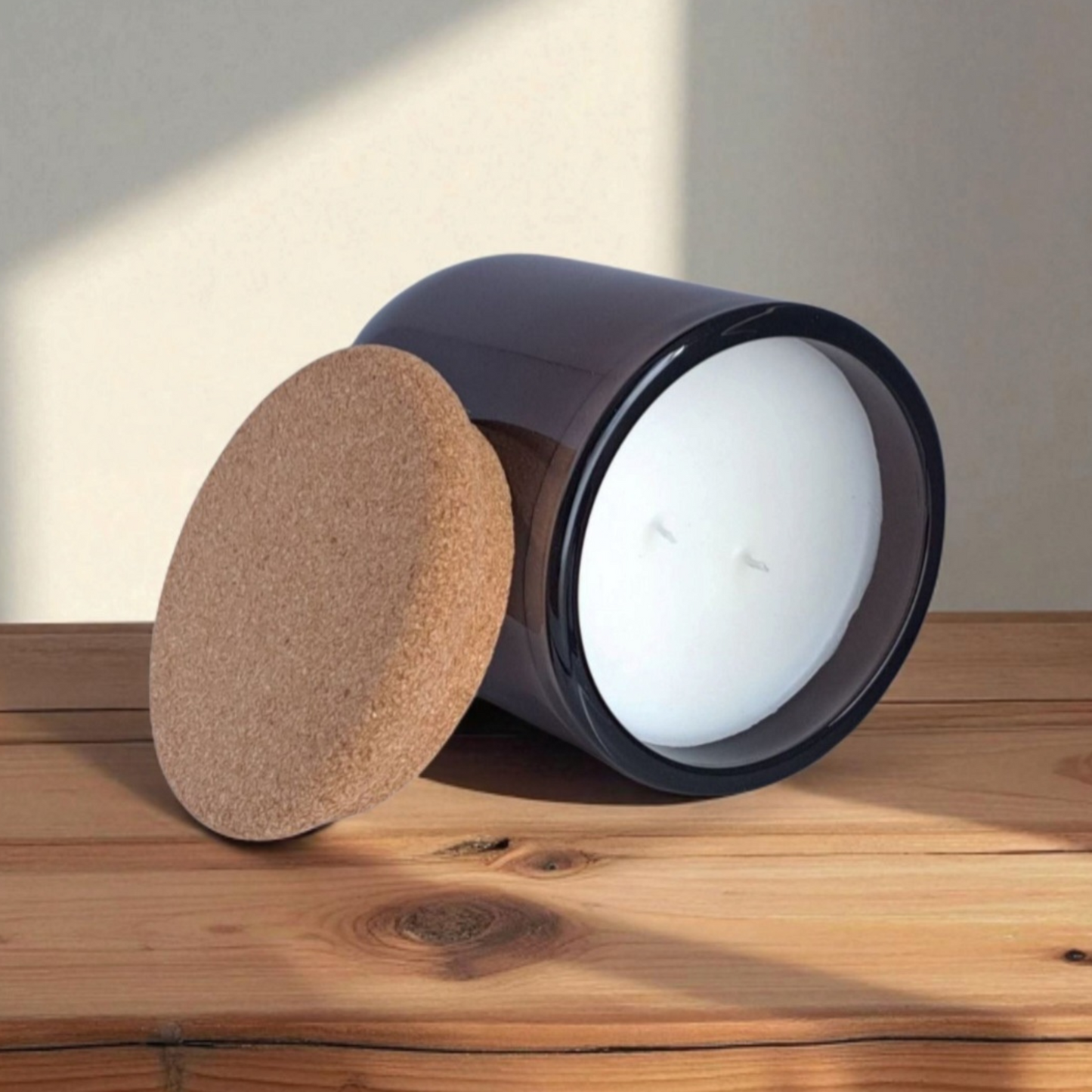 Mossfall candle in brown glass tilted to show natural cork lid and smooth wax surface with double wicks on wooden surface