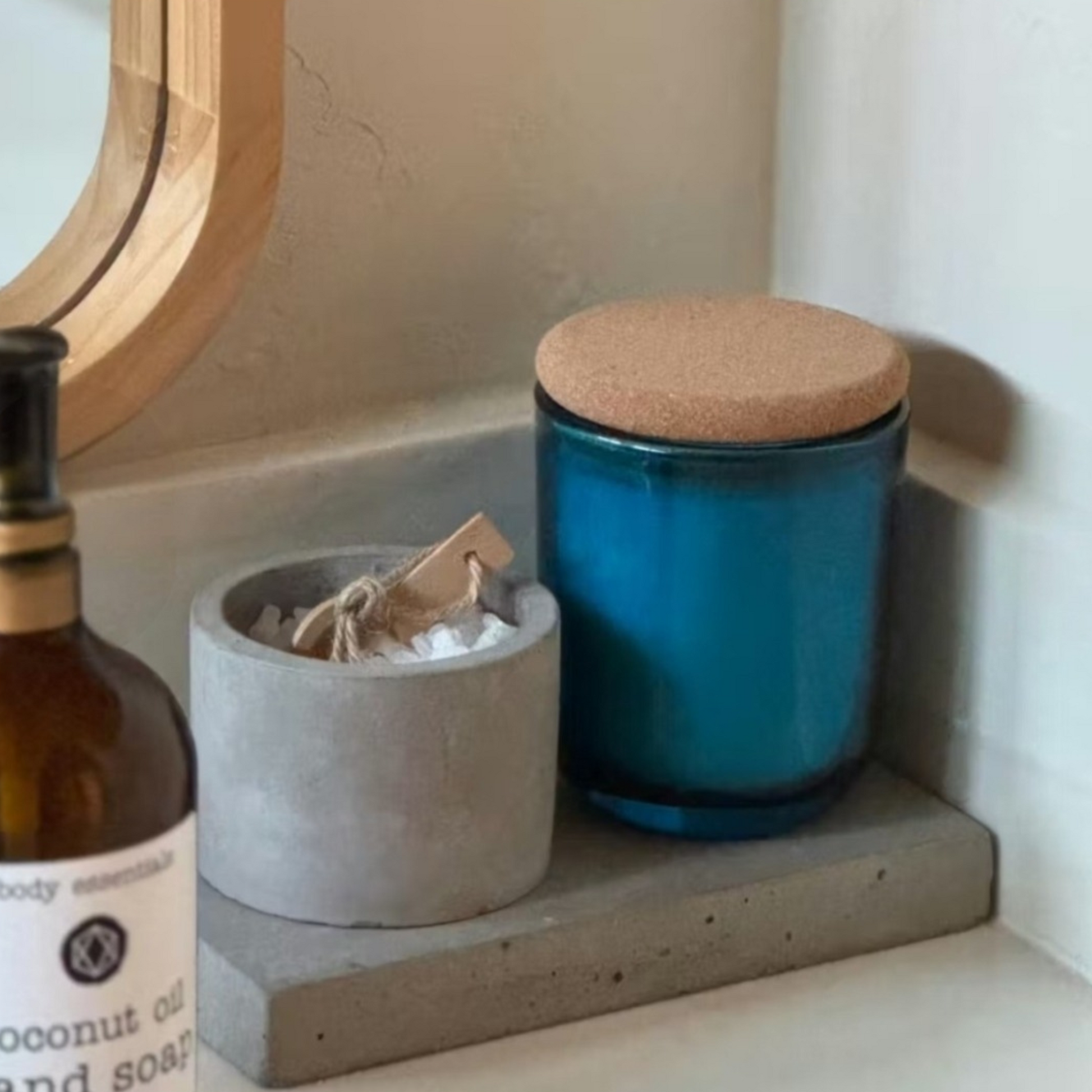 Saltmere blue glass candle with cork lid on bathroom shelf with natural bath products
