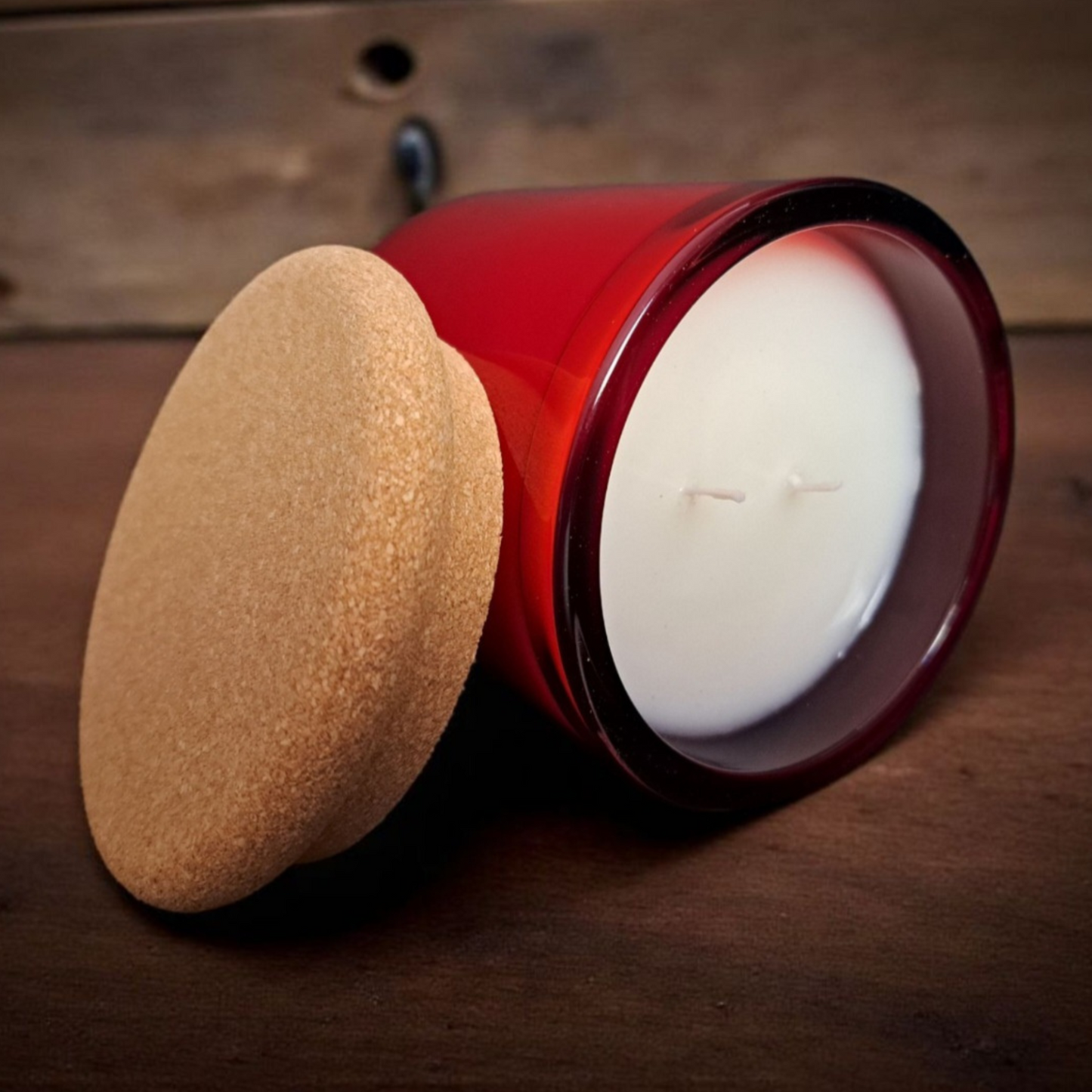 Close-up of Winter Reigns candle in red glass showing smooth wax surface and double wicks with cork lid