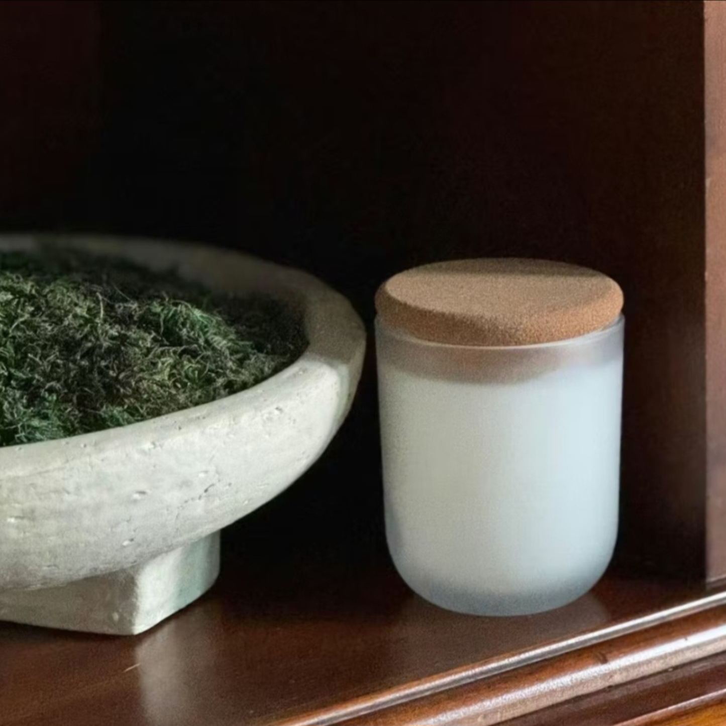 Orriswood frosted white glass candle with cork lid next to moss-filled ceramic bowl in styled home setting